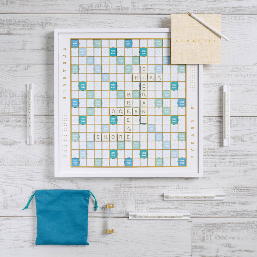 Scrabble board game box set up on wood surface, the board is a white base with various shades of teal blue squares in the play area, Hosting and Gathering, The Elevated Guest gift set