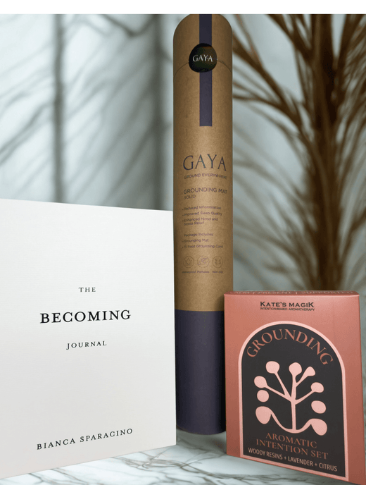 The Becoming' journal, GAYA grounding  mat, and Grounding aromatherapy spray bottles styled on marble, Grounding gift set
